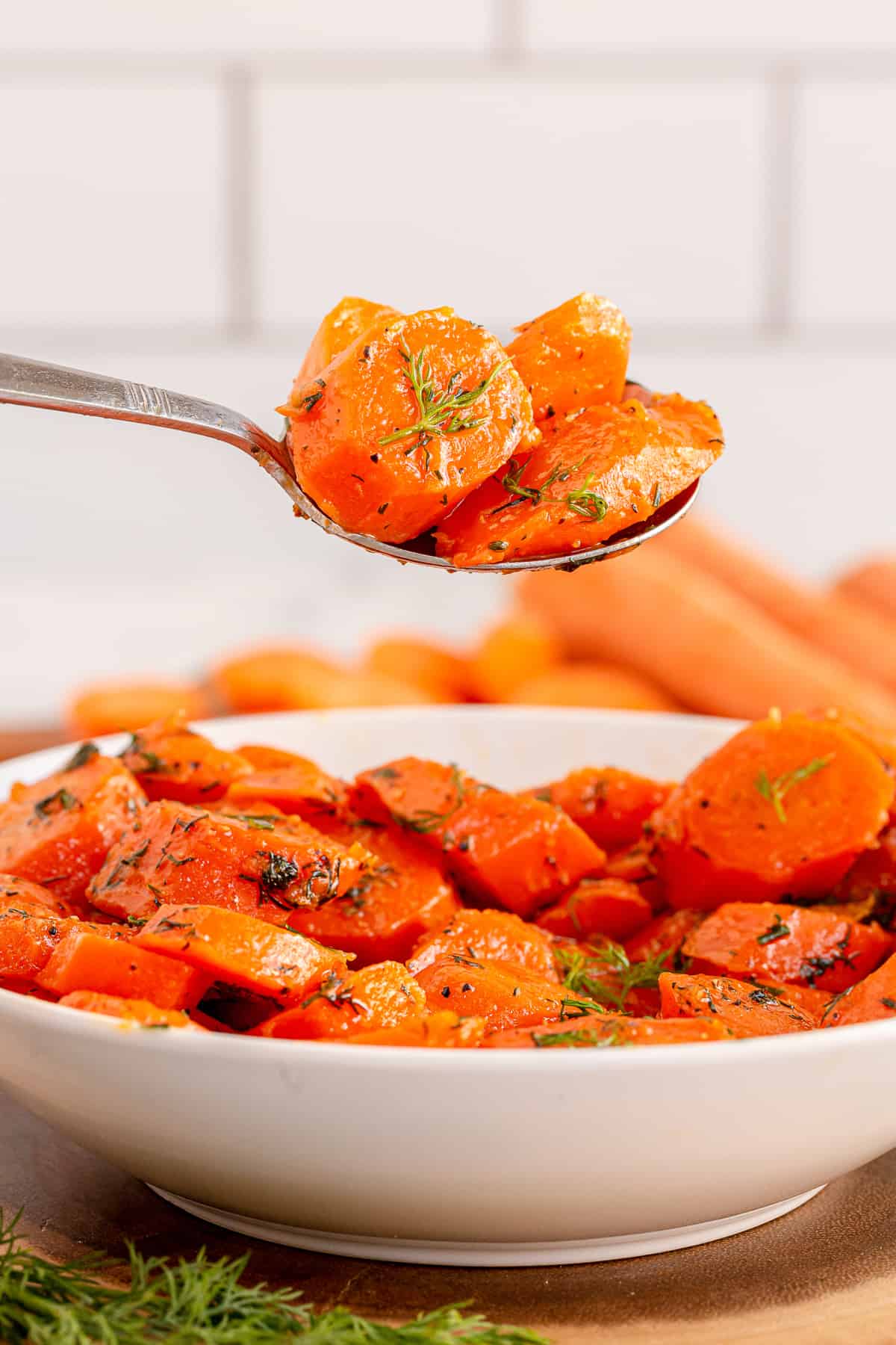 A spoon lifts a scoop of Brown Sugar Dill Carrots.