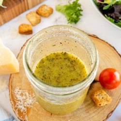 A mason jar filled with Italian Salad Dressing on a wood block.