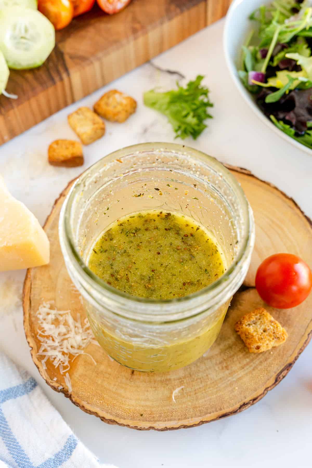 Italian Salad Dressing in an open mason jar with on a wood block.