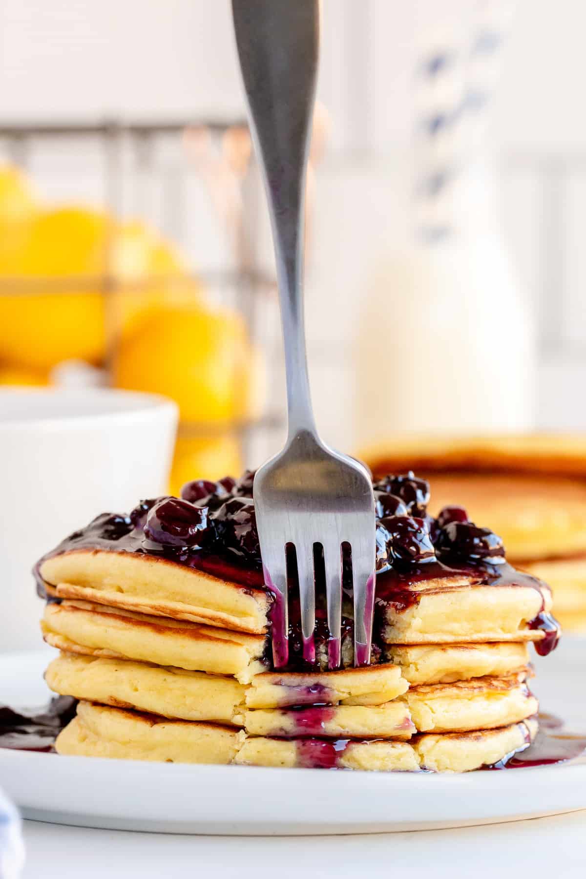 A fork breaks into a stack of pancakes.