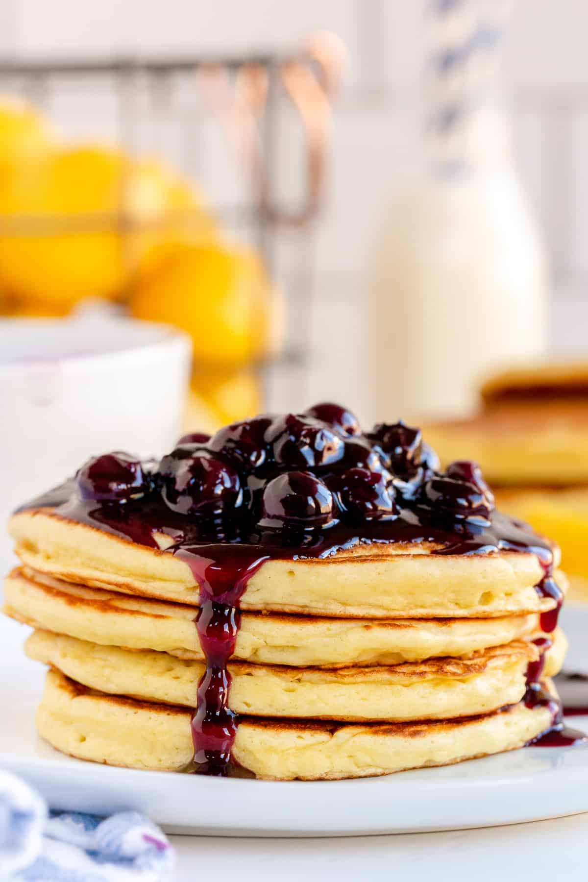 A stack of pancakes with blueberry sauce running down the sides.