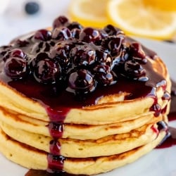 A stack of pancakes with blueberry sauce dripping down the sides.