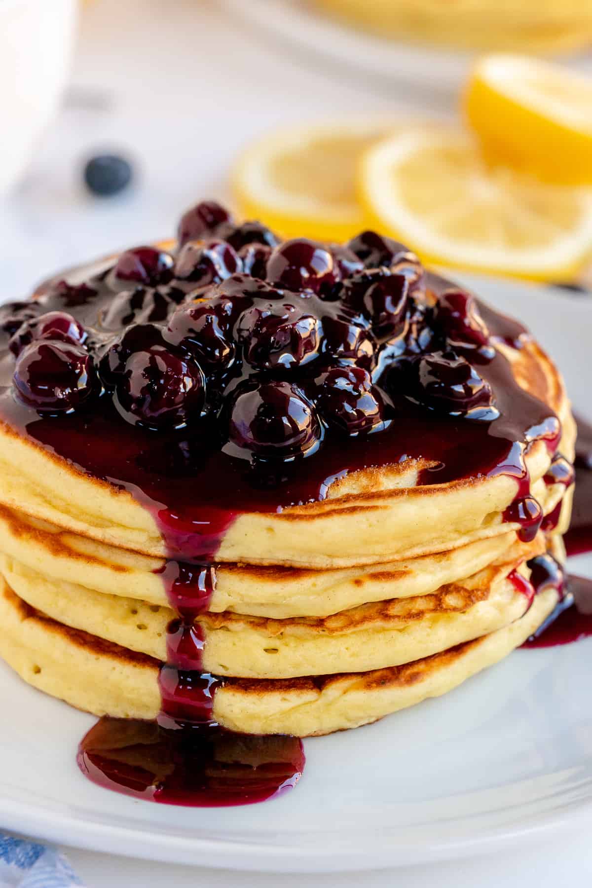 A stack of pancakes with blueberry sauce dripping down the sides.