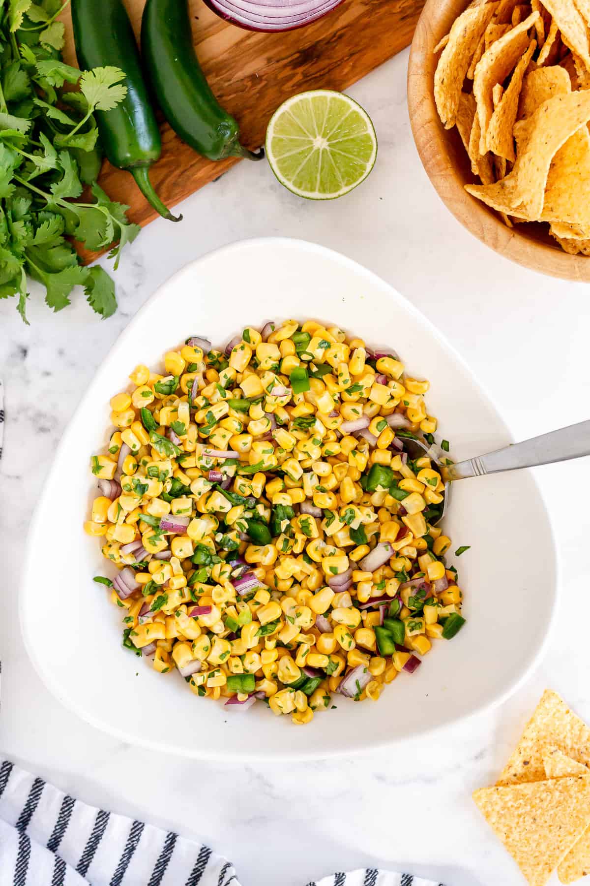 Corn Salsa in a white serving bowl with a spoon.