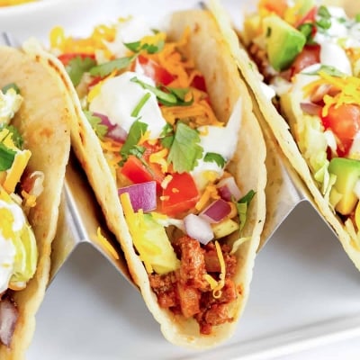 Three ground beef tacos in a taco stand.