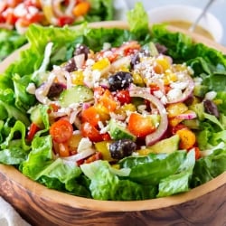 Greek Salad with tomatoes, onions, and kalamata olives in a wooden bowl.