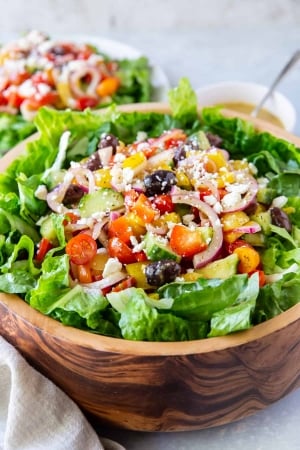 Greek Salad with tomatoes, onions, and kalamata olives in a wooden bowl.