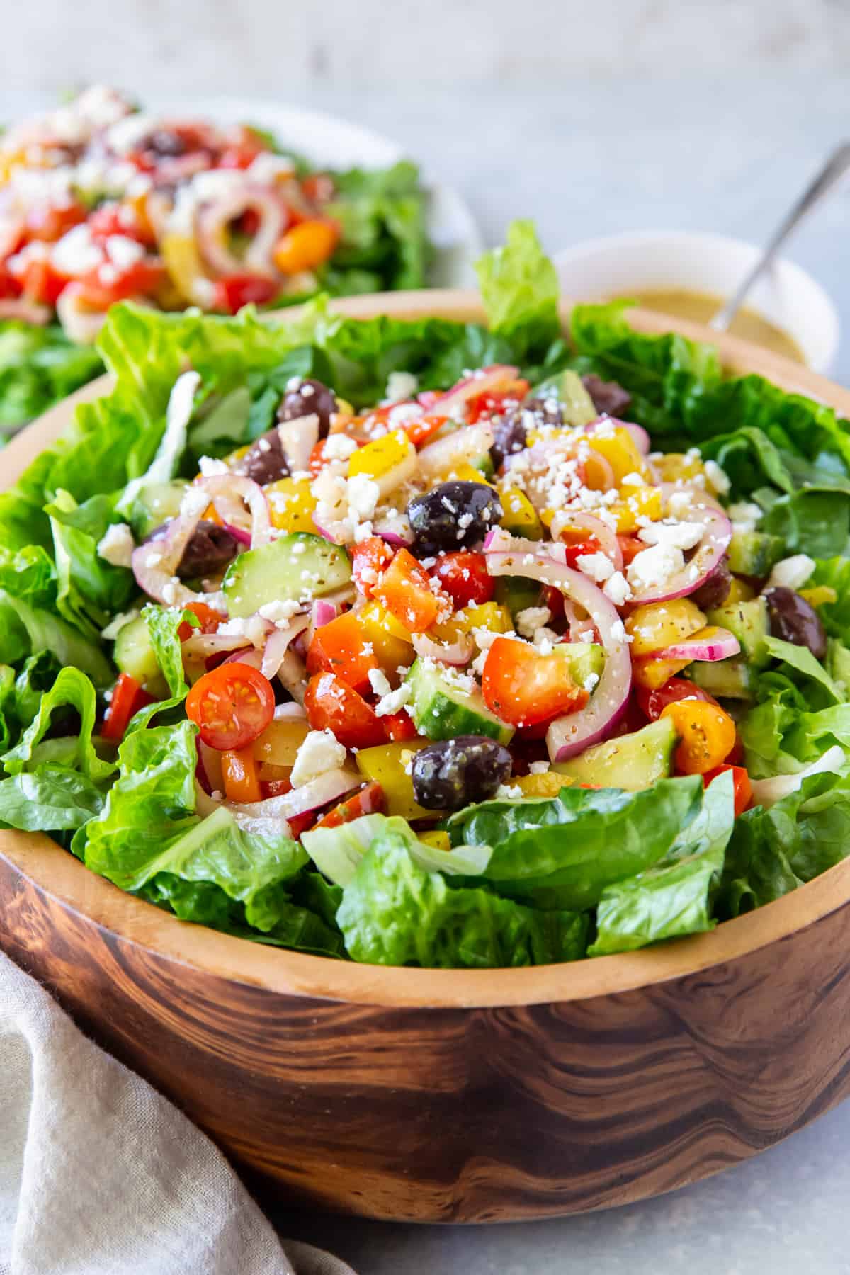Greek Salad with tomatoes, onions, and kalamata olives in a wooden bowl.