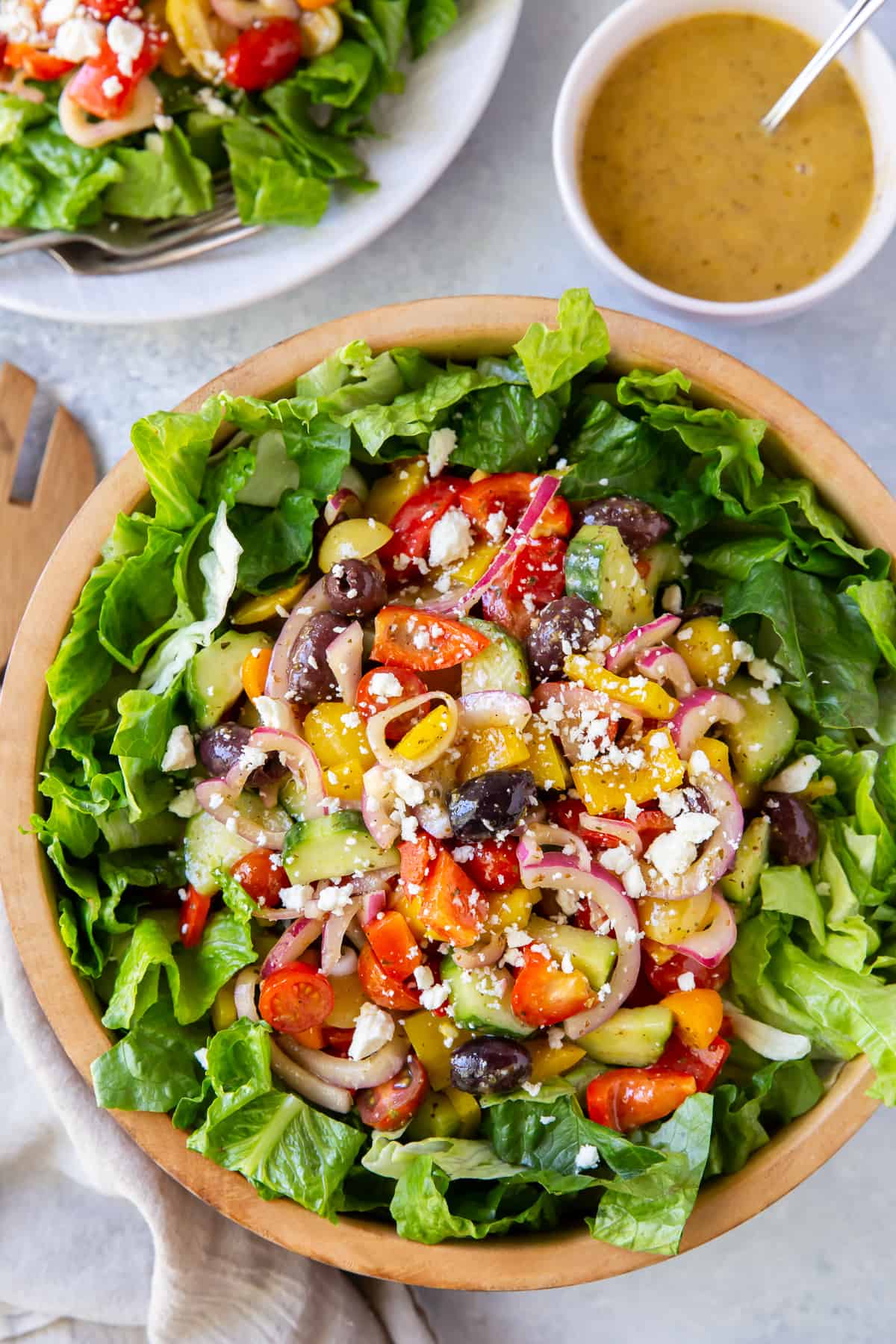 A colorful salad shot from over the top with a bowl of dressing next to it.