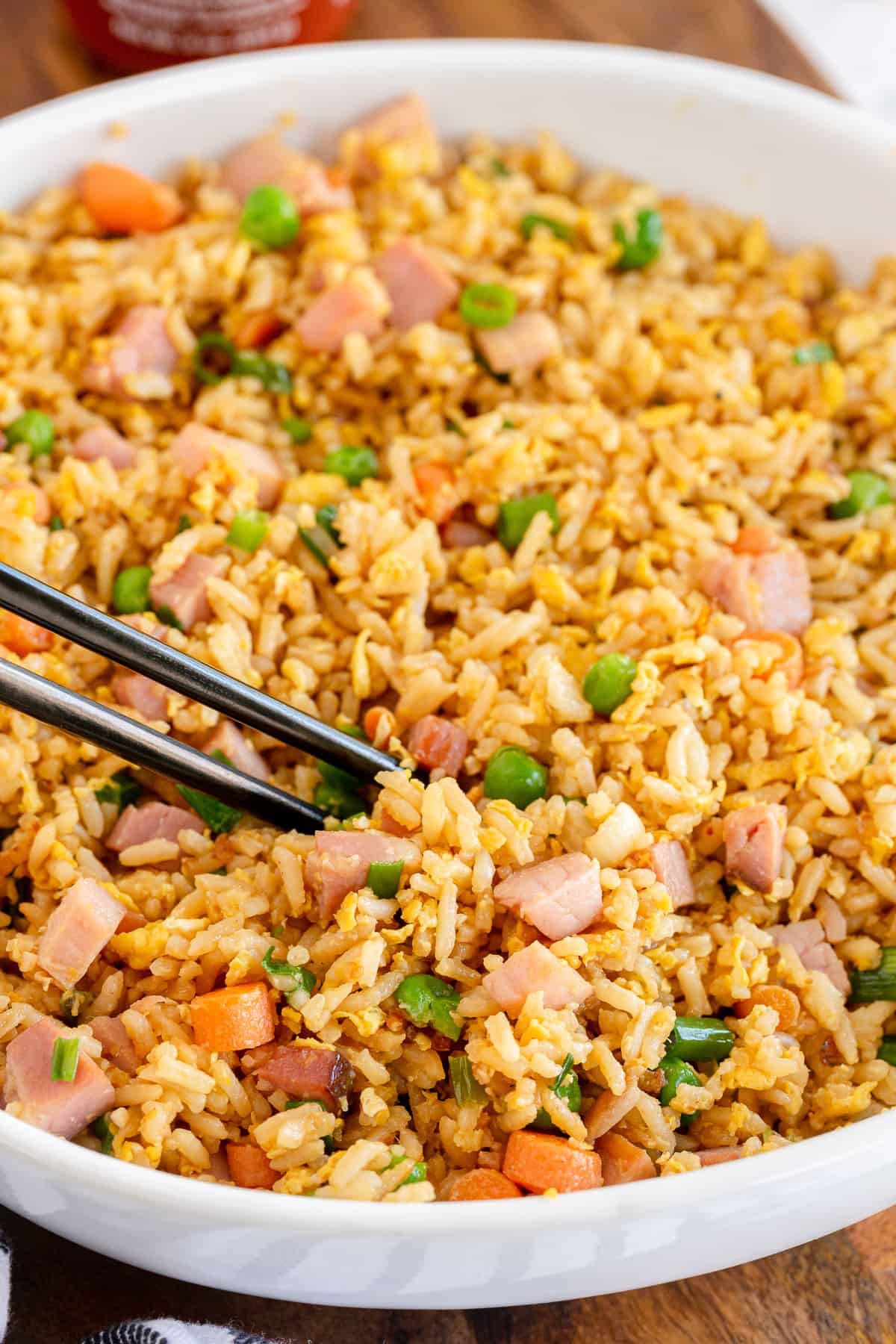 Chopsticks dig in to a bowl of fried rice with ham.