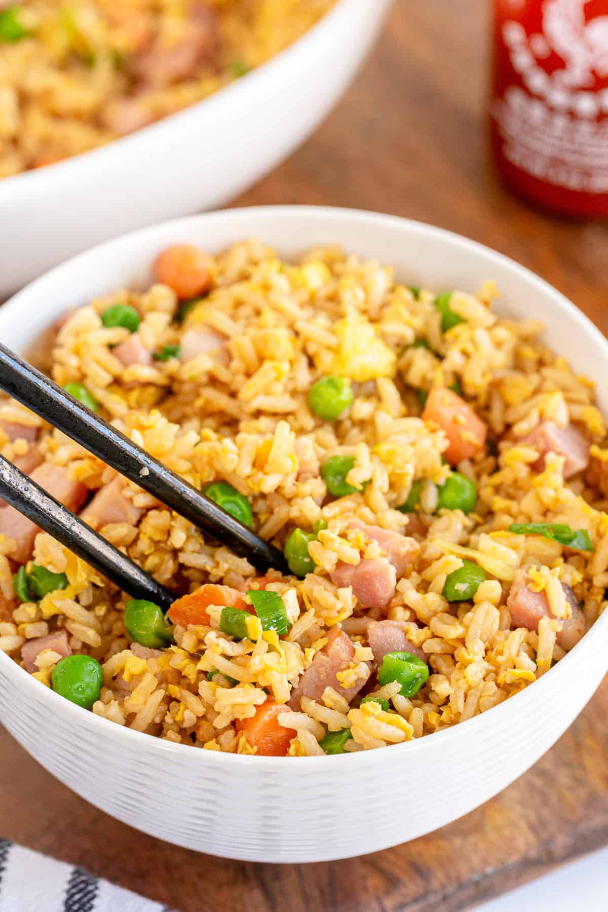 Chopsticks in a bowl of fried rice with ham.