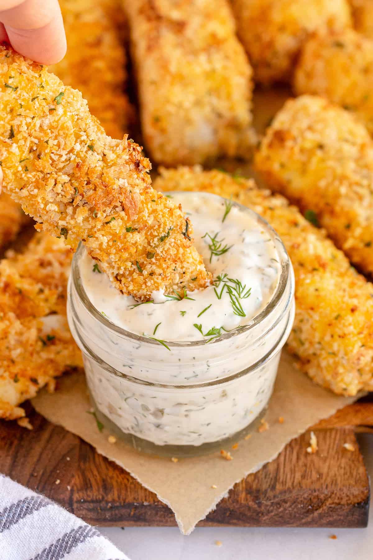 A fish stick dipping into a jar of tartar sauce.