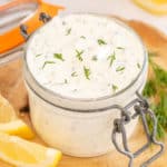 Tartar sauce topped with fresh dill in a small glass jar.