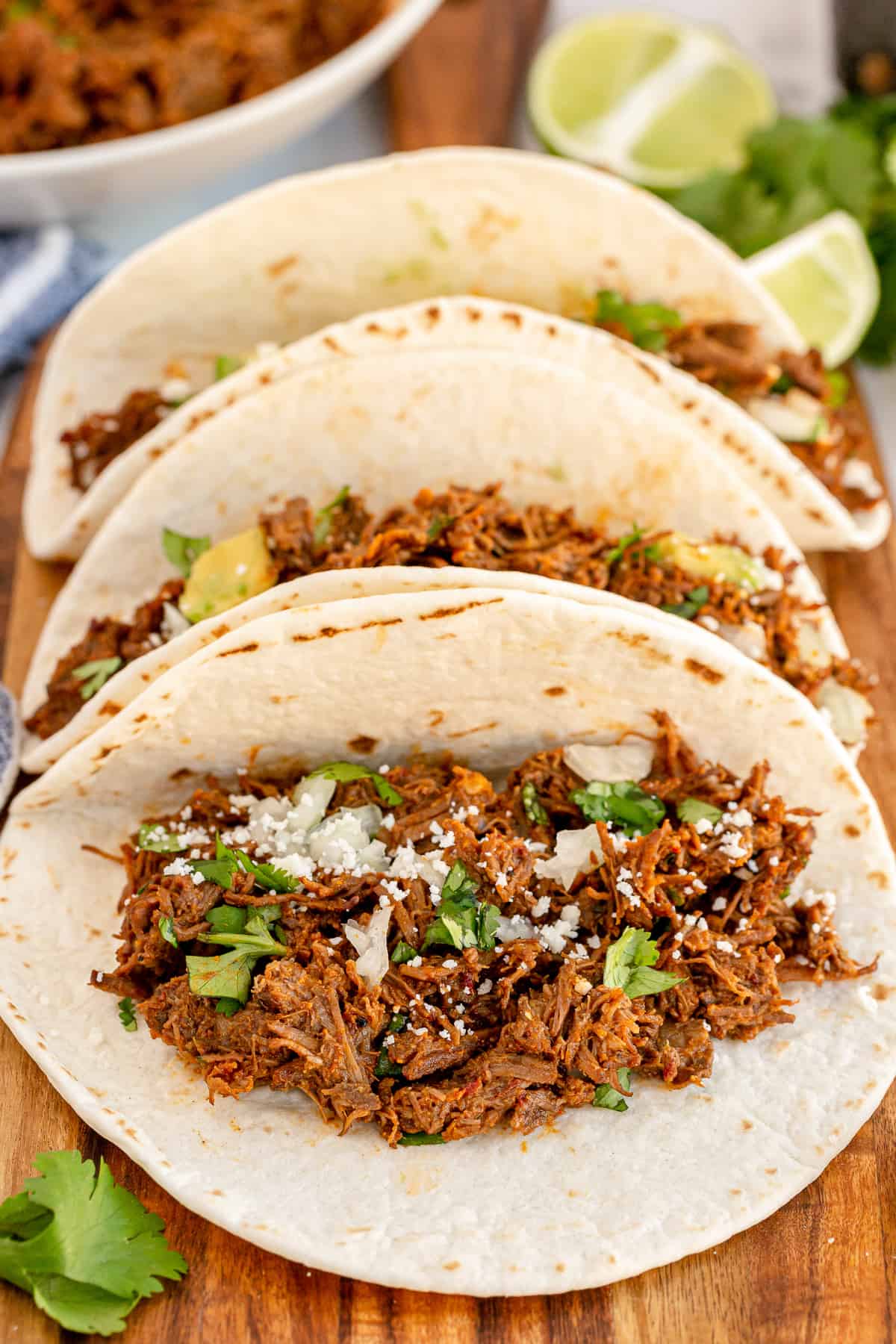 Three tortillas stuffed with barbacoa, onion, and cilantro.