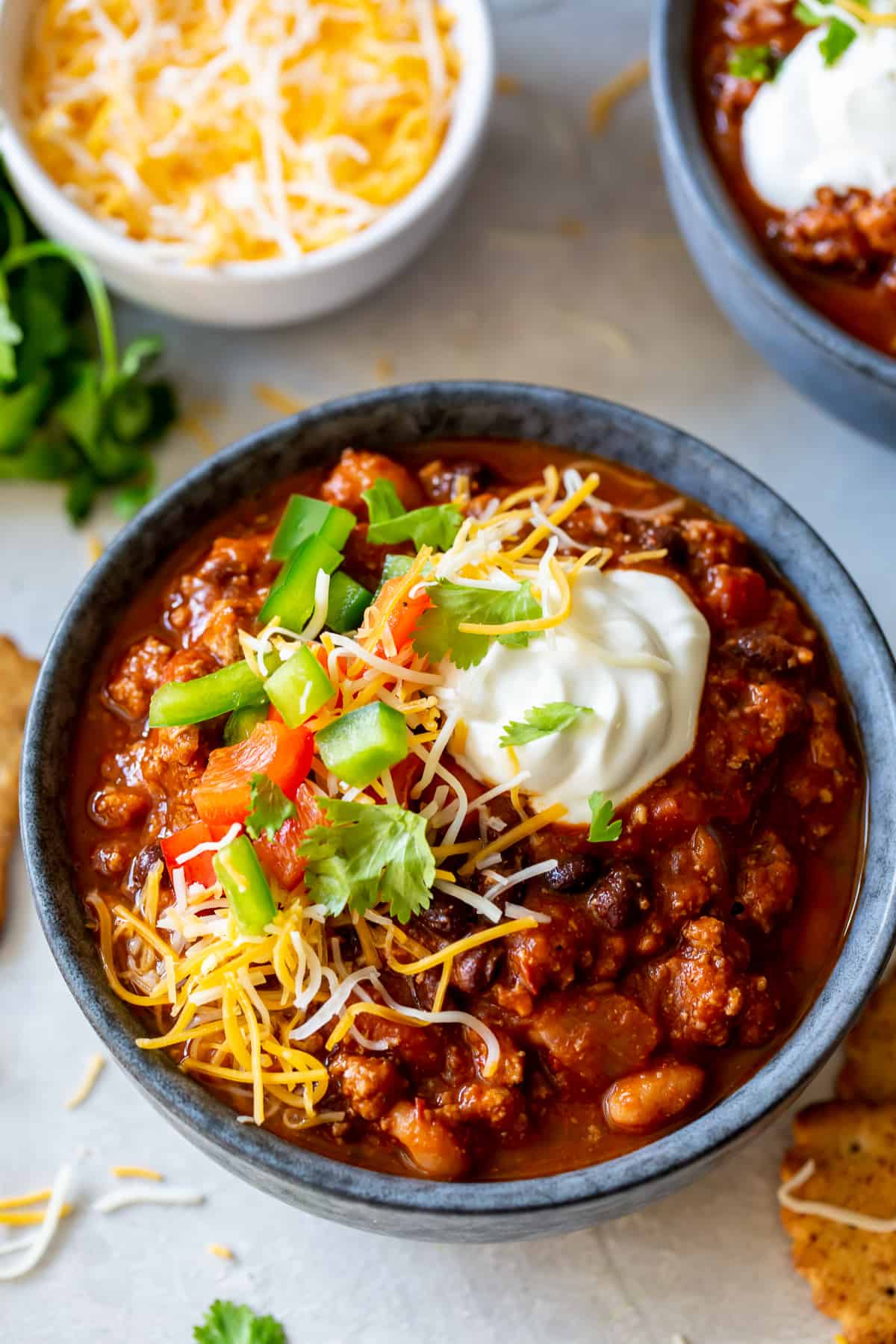 A bowl of turkey chili topped with cheese and peppers.
