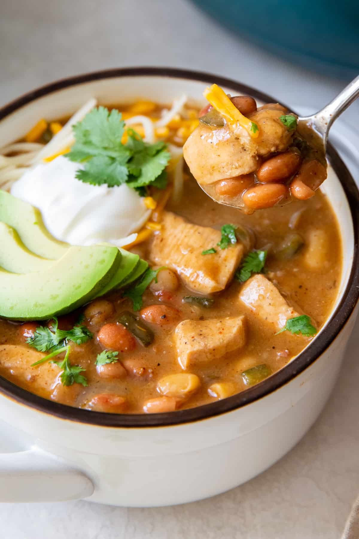 A spoon hovers over a bowl of chili.