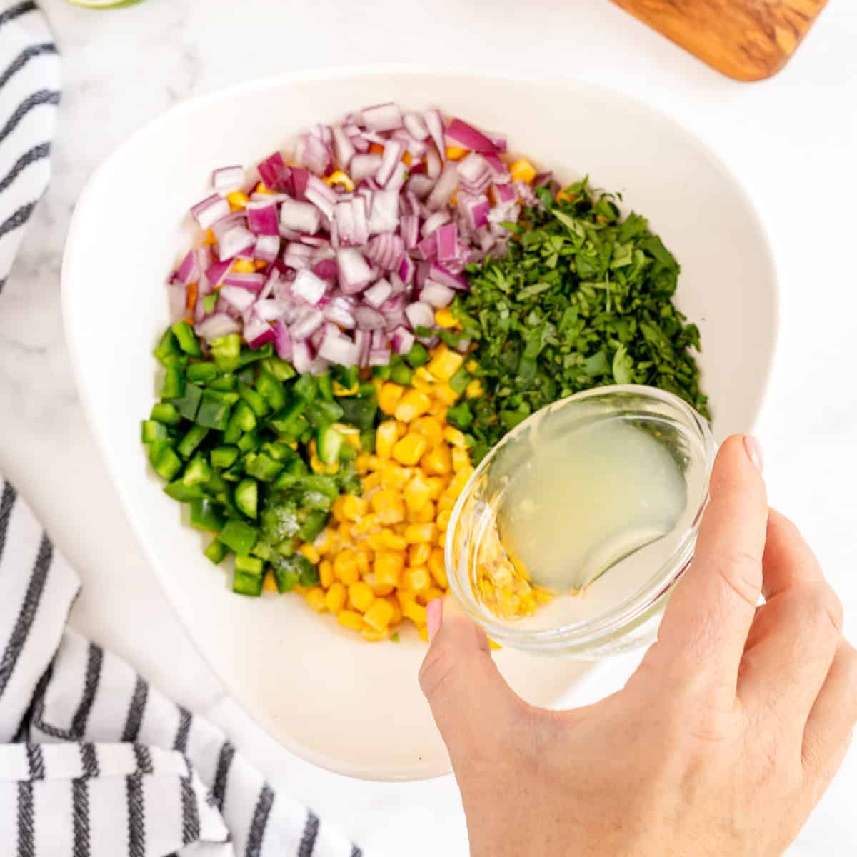 Adding fresh lime juice to homemade Chipotle corn salsa made with frozen sweet corn.