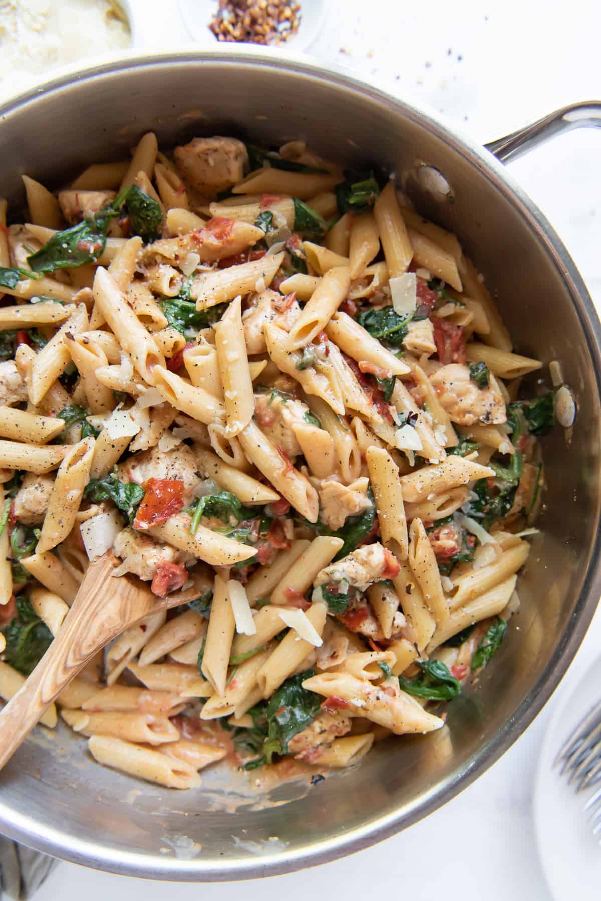 A skillet of pasta with a wooden spoon shot from over the top.