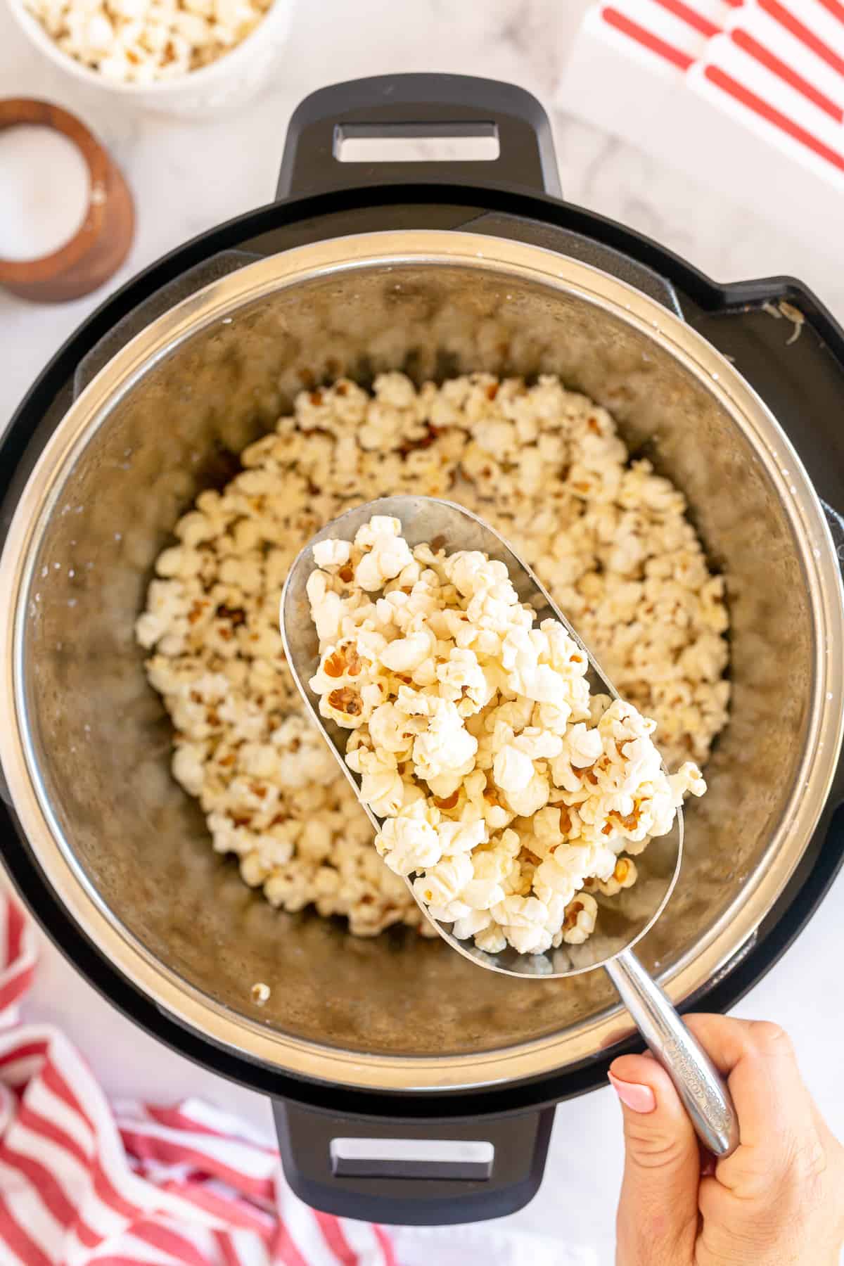 A metal scoop scoops popcorn from an Instant Pot.