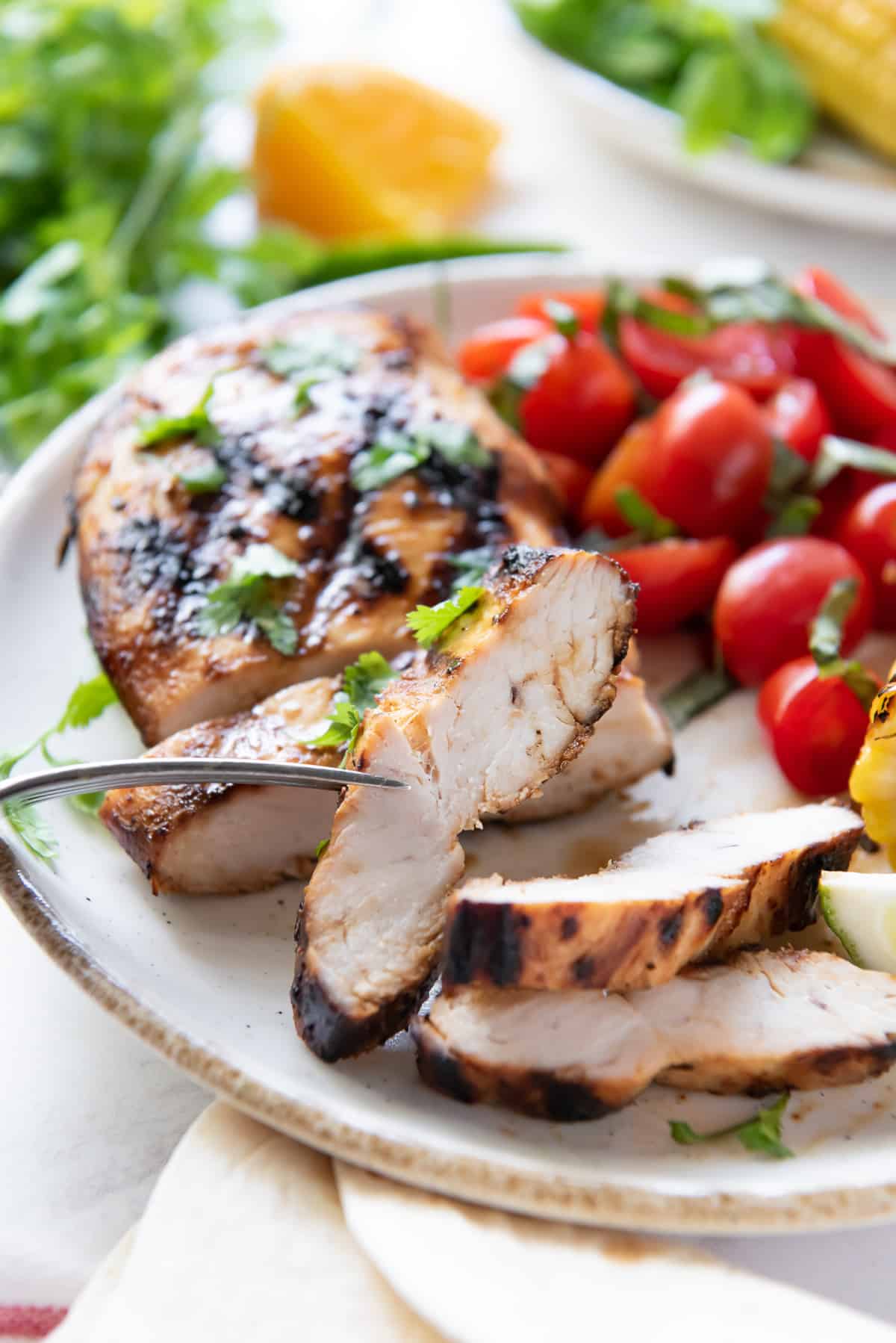 A fork piercing a slice of grilled chicken.