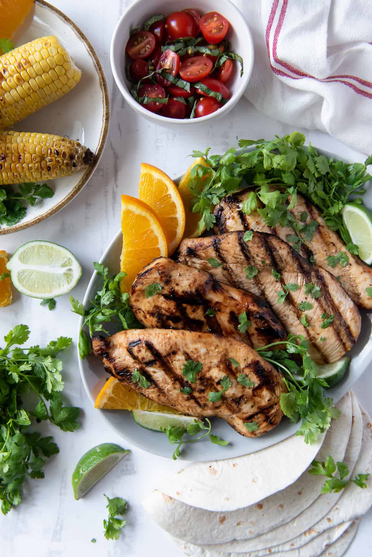 A platter of grilled chicken with cilantro and oranges shot from over the top.