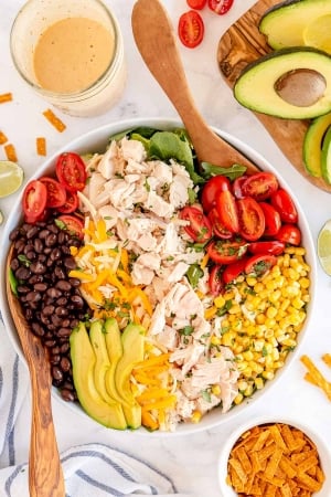 A salad with chicken, avocado, black beans, corn, and tomatoes shot from over the top.