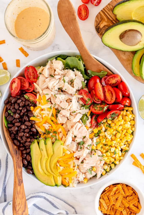 A salad with chicken, avocado, black beans, corn, and tomatoes shot from over the top.