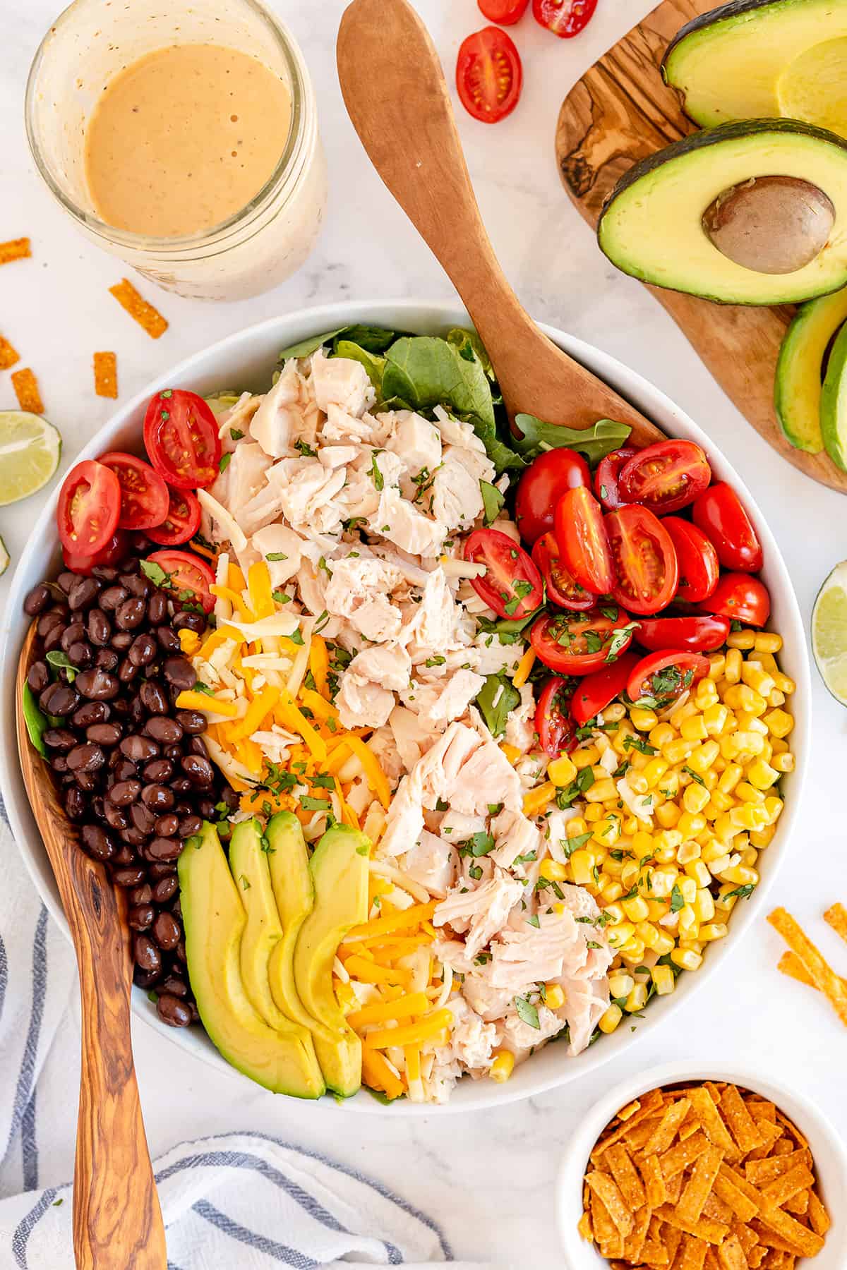 A salad with chicken, avocado, black beans, corn, and tomatoes shot from over the top.