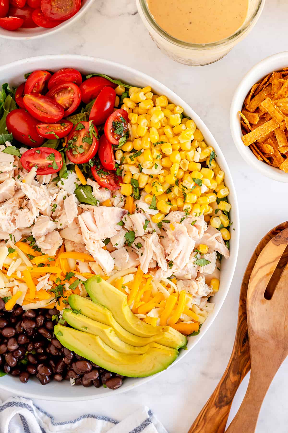 Corn, beans, avocado, tomato, chicken, and cheese in a salad bowl.