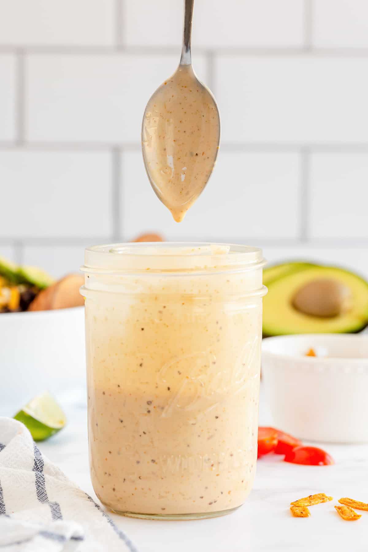 A spoon and a mason jar filled with Southwest Caesar Salad Dressing.