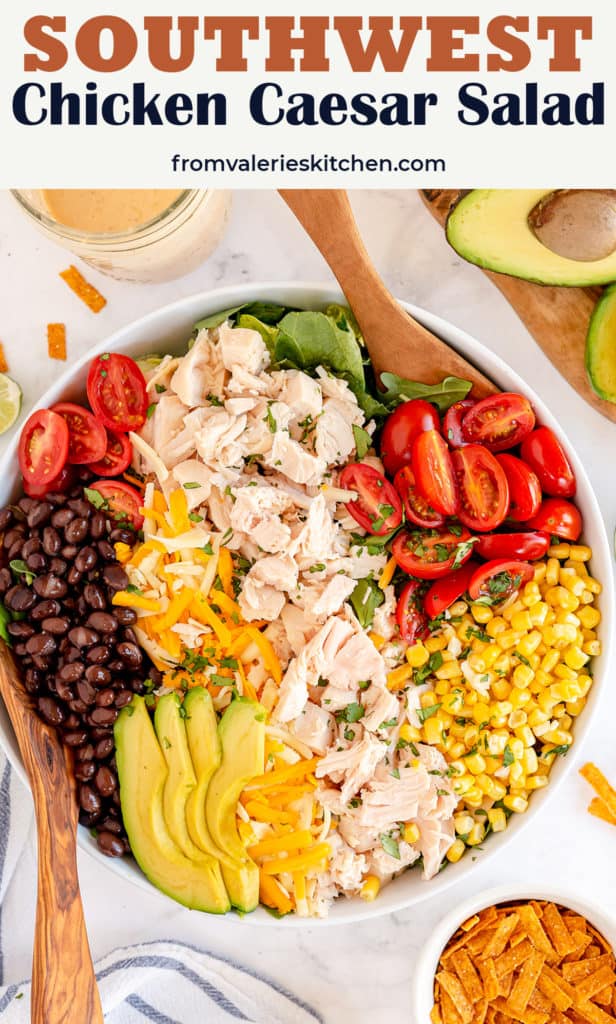 Salad spoons tucked into a serving bowl filled with Southwest Chicken Caesar Salad with text overlay.