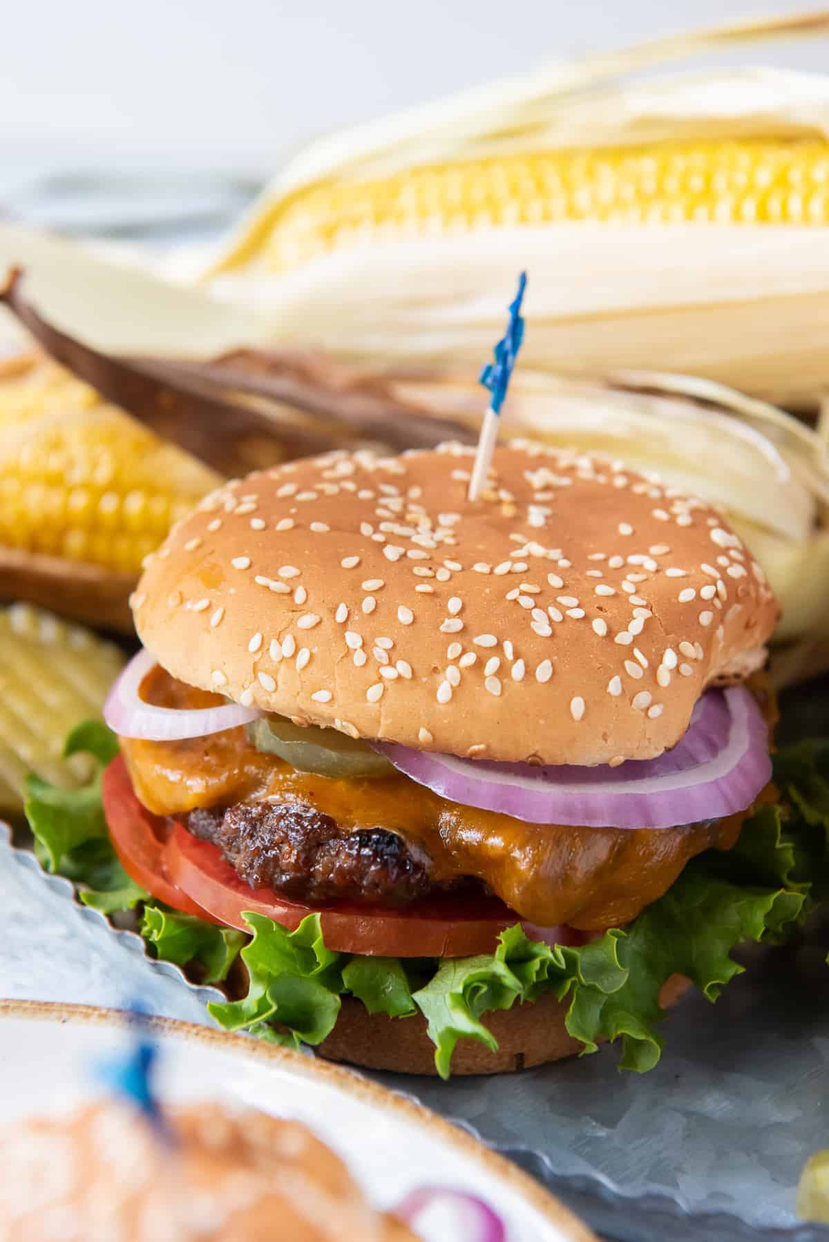 A cheeseburger with onions, tomatoes and lettuce on a sesame seed bun.