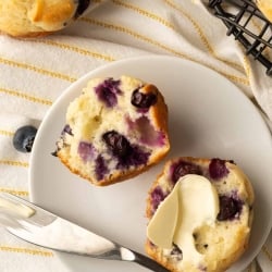 A blueberry muffin cut in half and smeared with butter.
