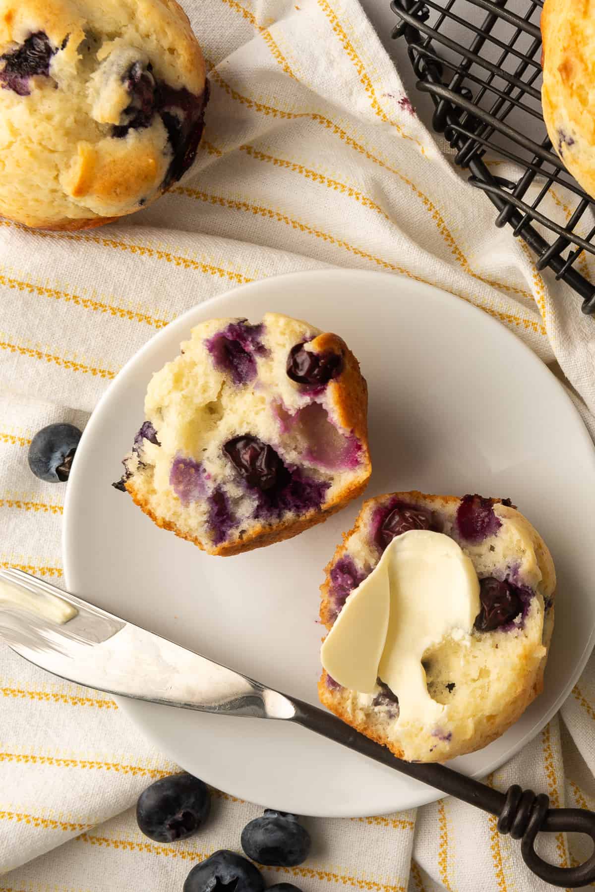 A blueberry muffin cut in half and smeared with butter.