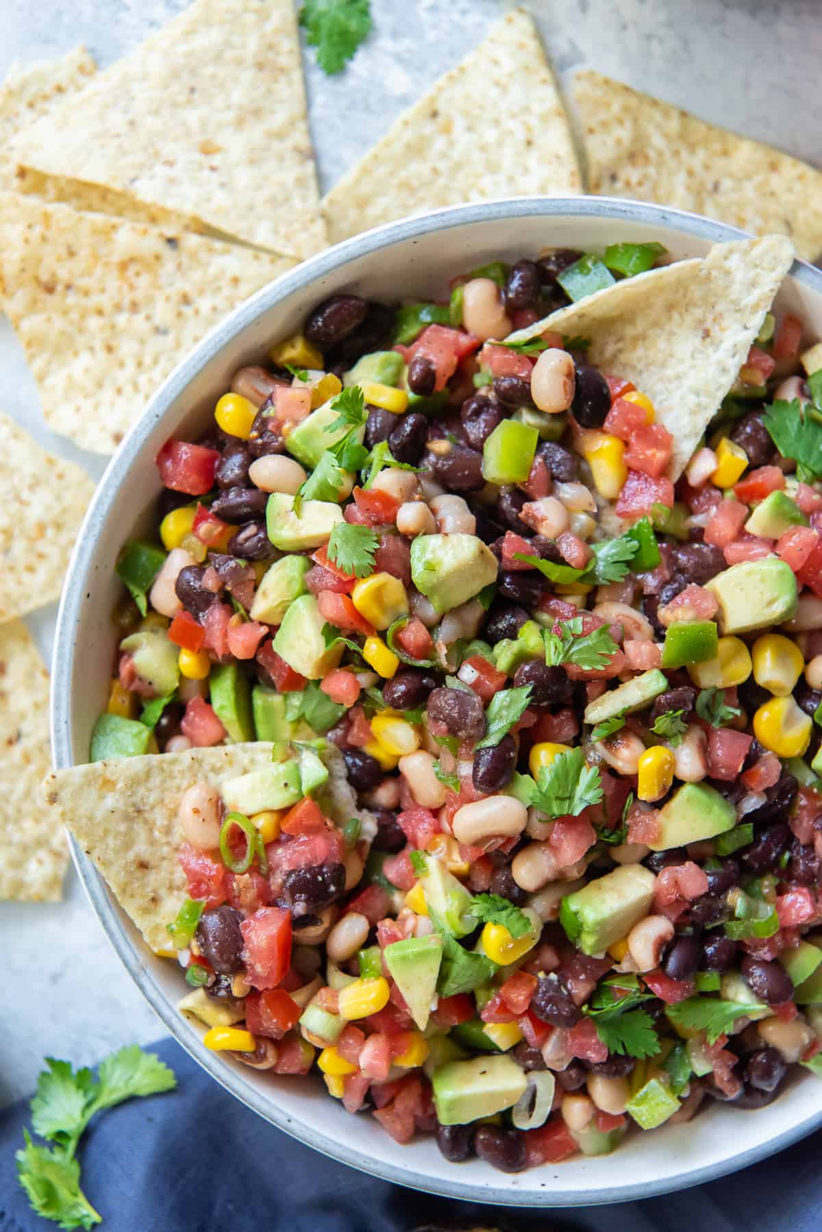 Tomatoes, avocado, corn and black beans in a bowl with tortilla chips.