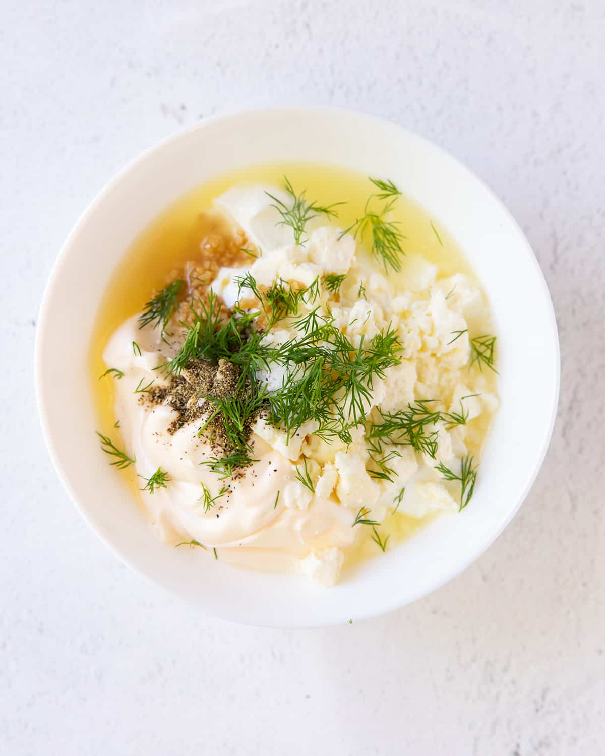Greek yogurt, dill, lemon, and garlic in a small white bowl.