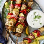 Greek Chicken Kabobs on a silver platter with Feta Dill Sauce.