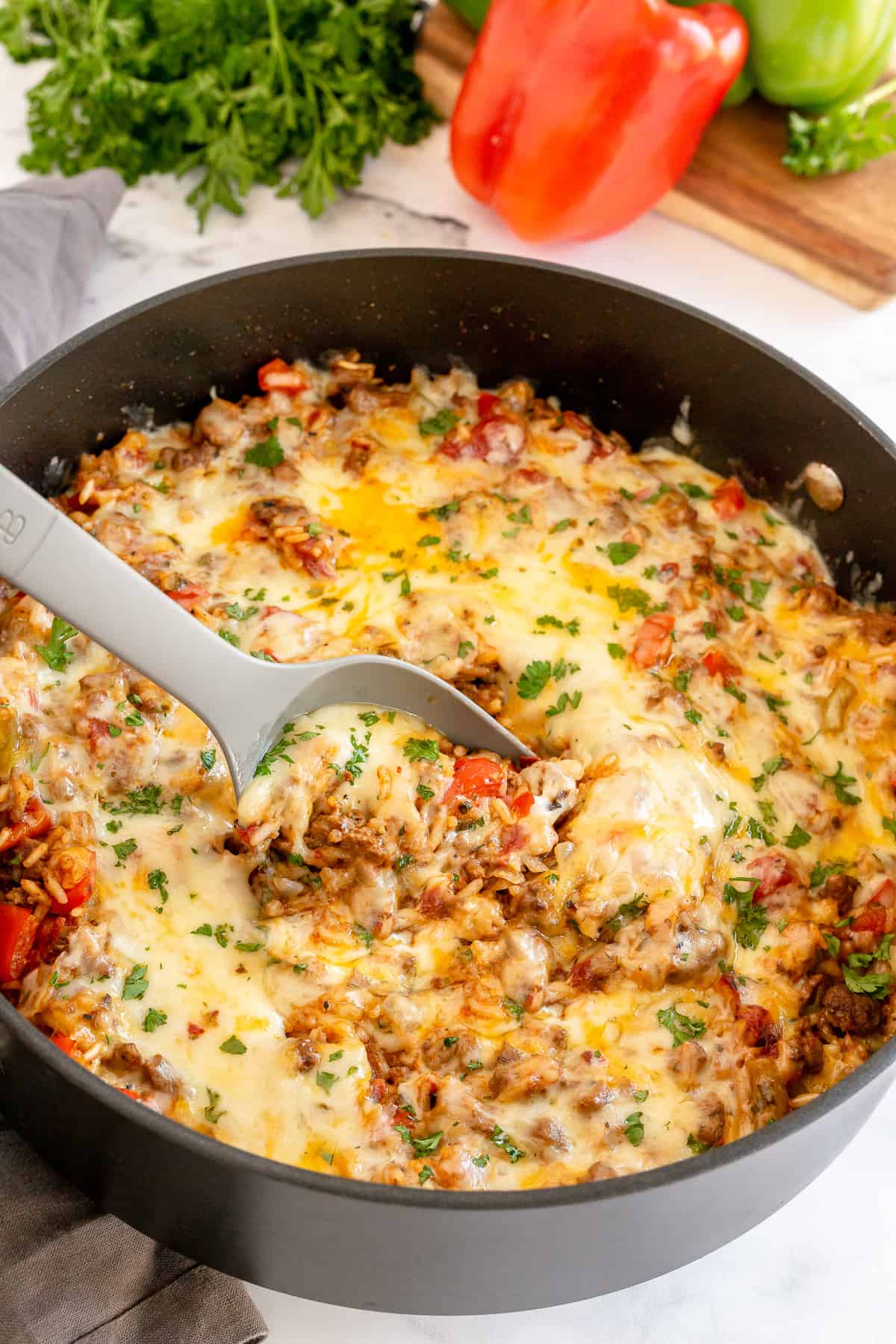 A spoon scoops a stuffed pepper mixture from a skillet.