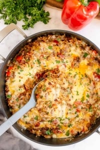 A spoon scoops a stuffed pepper mixture from a skillet.