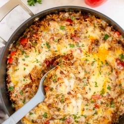 A spoon scoops a stuffed pepper mixture from a skillet.