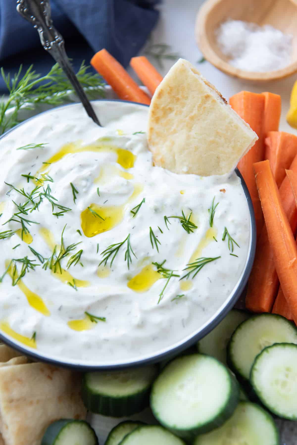 A piece of pita dipped into a bowl of Tzatziki.