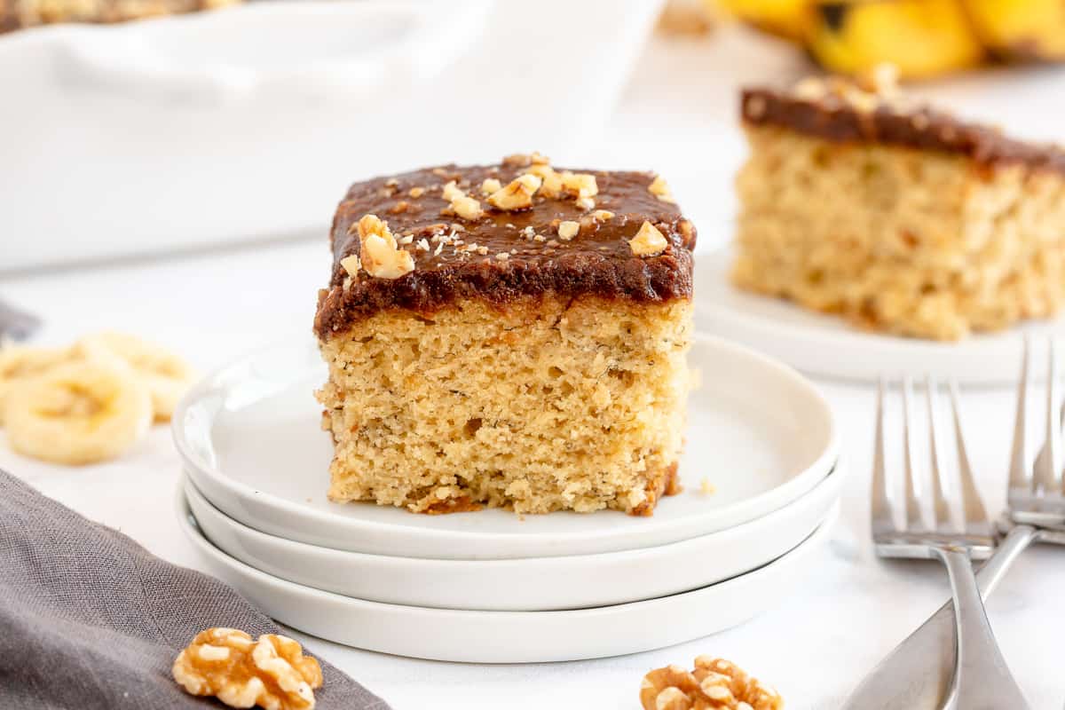 A slice of Banana Cake on a stack of white plates.