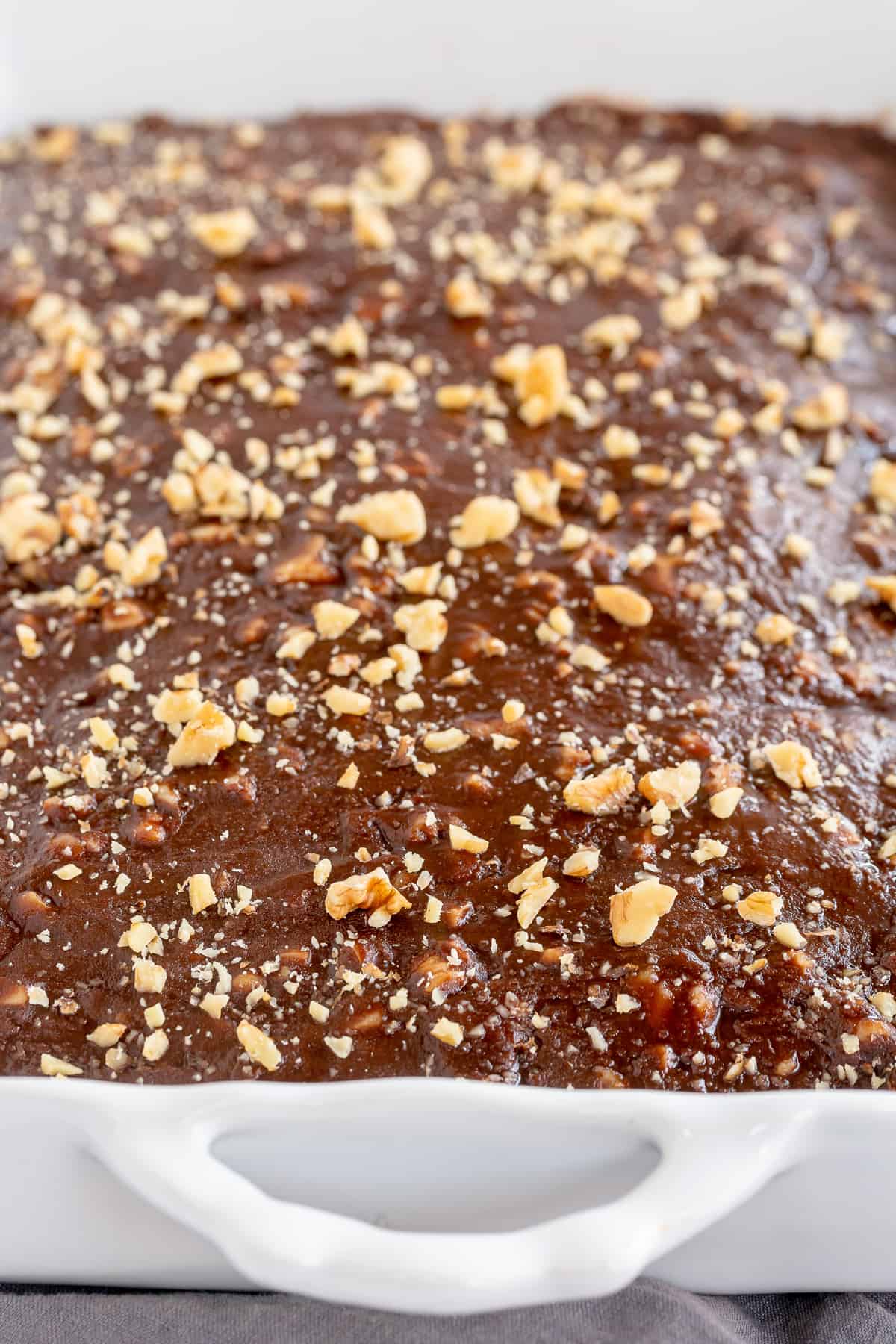 A close up of a cake with chocolate frosting and walnuts.