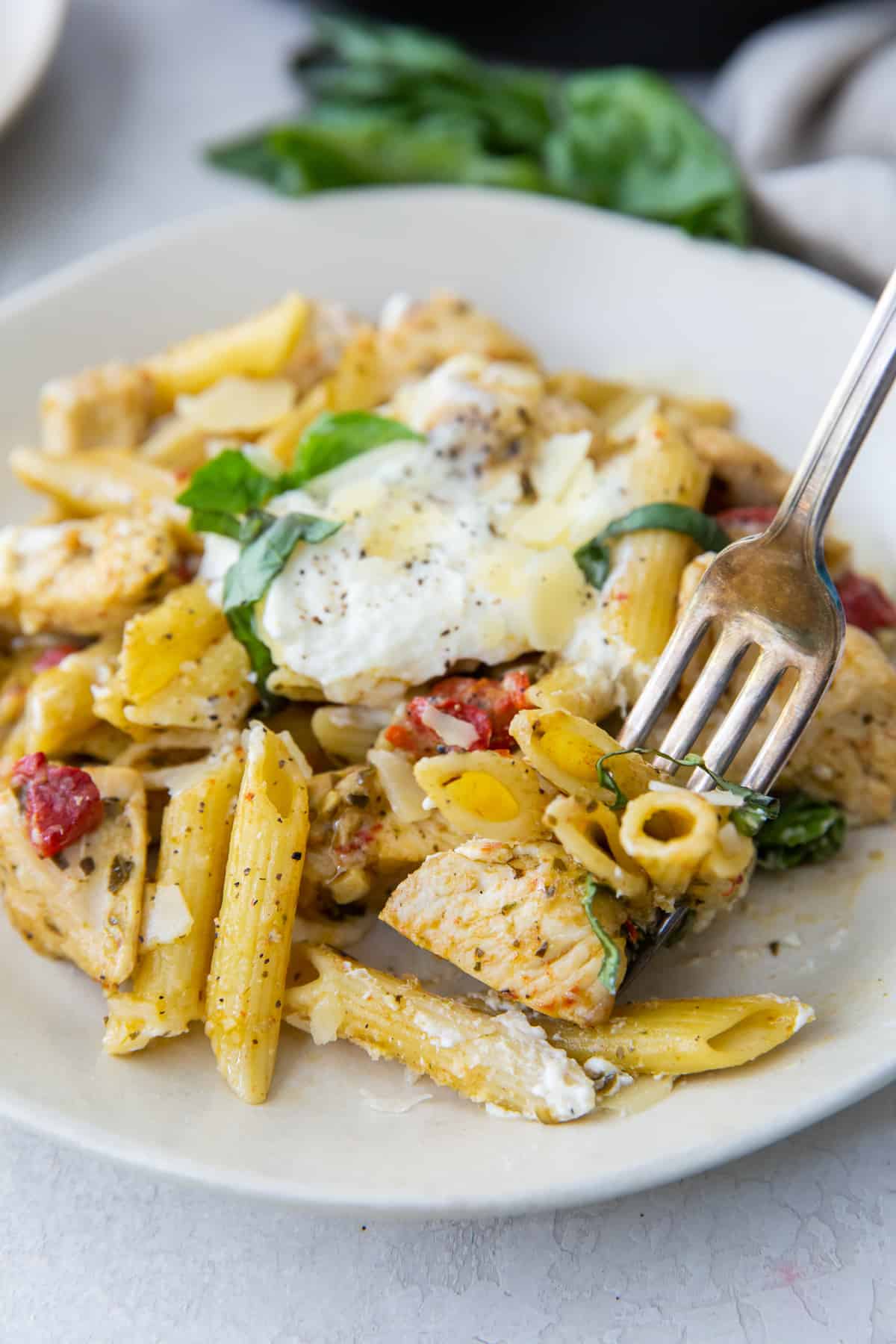 A fork digs into a plate full of Chicken Penne Pasta.