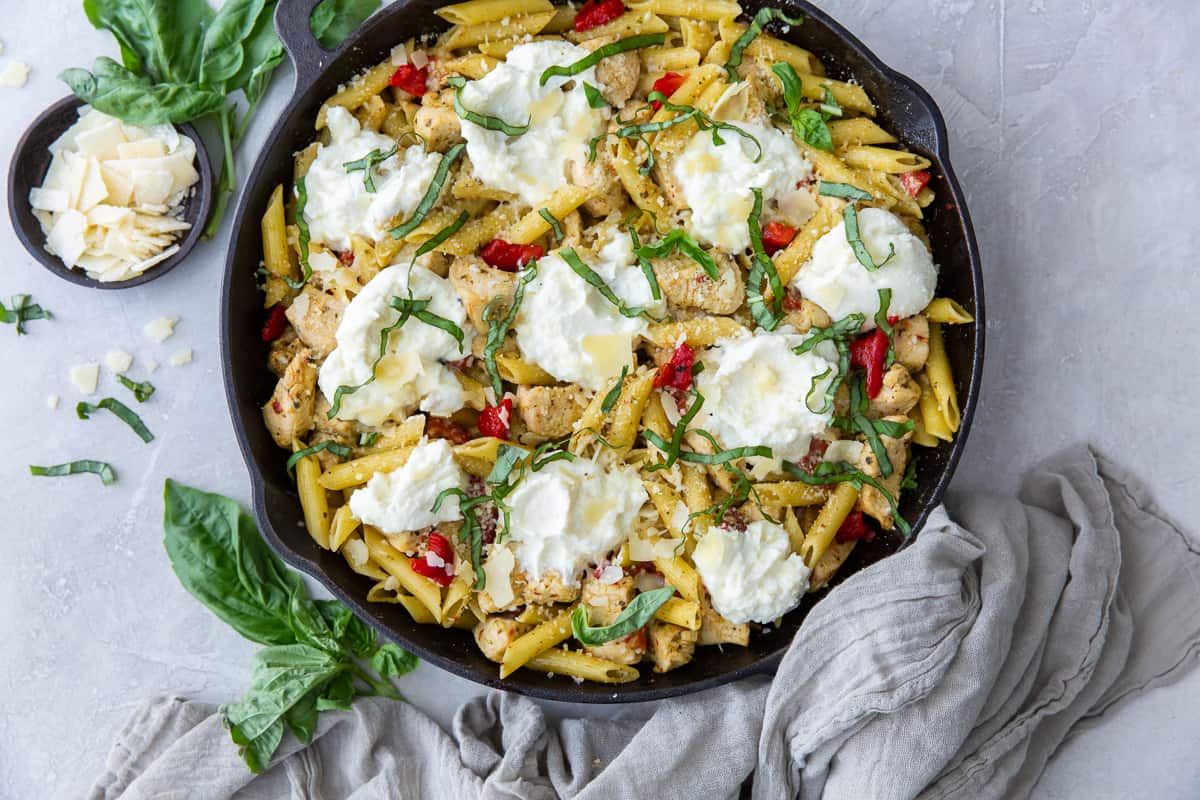 A grey cloth draped over the handle of a skillet filled with pasta.