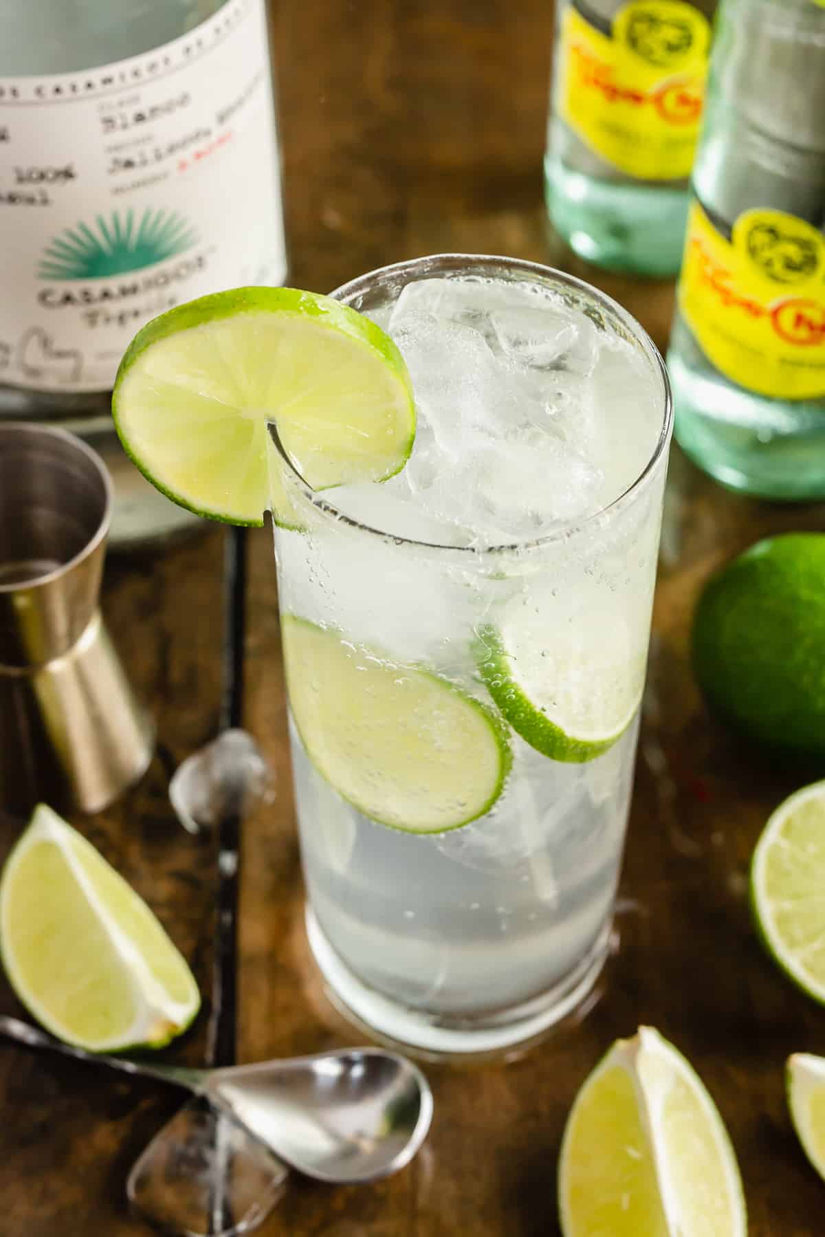 A Ranch Water cocktail in a tall glass with ice and lime slices.