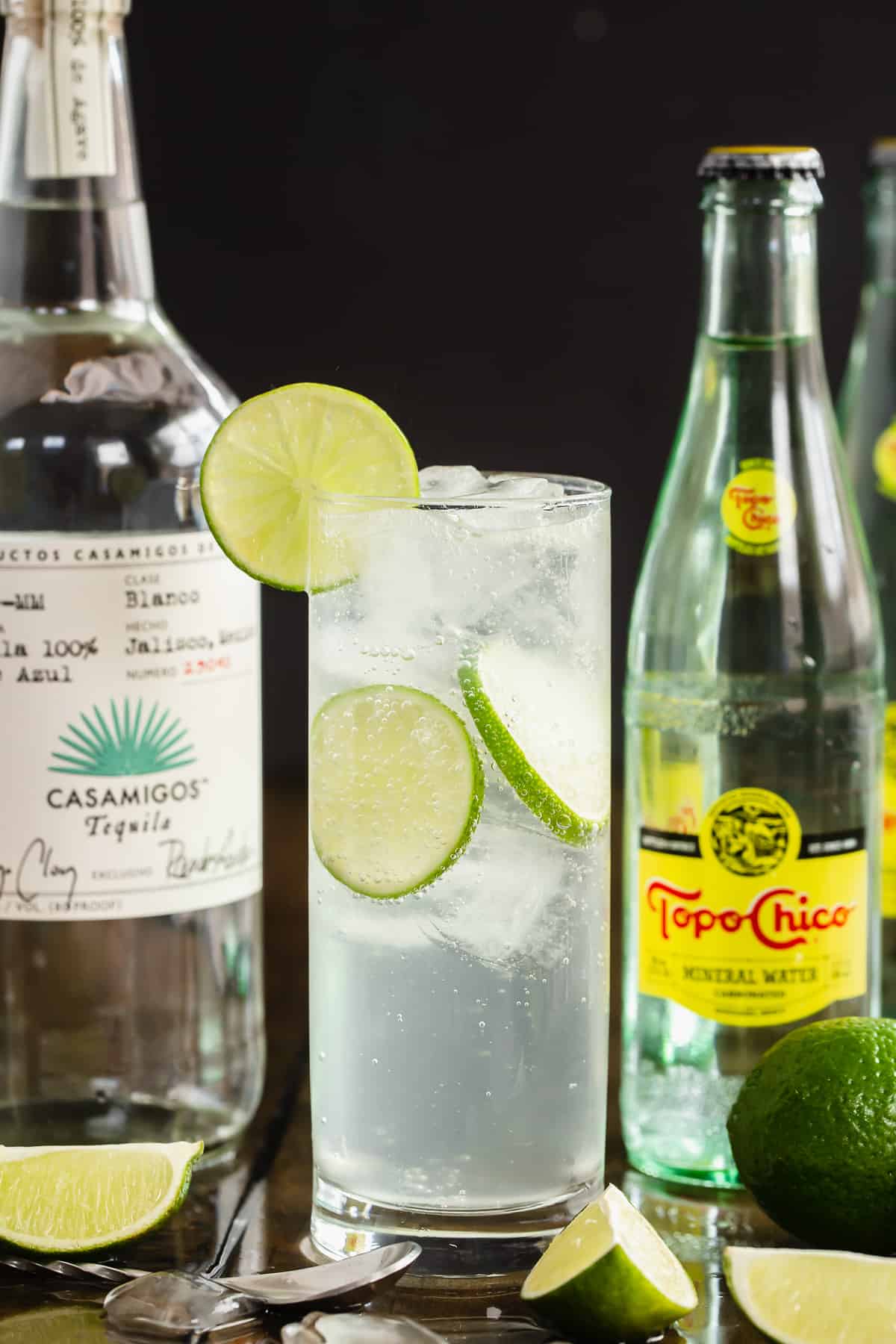 An Ranch Water cocktail in front of a bottle of Casamigos Tequila and Topo Chico Mineral Water.