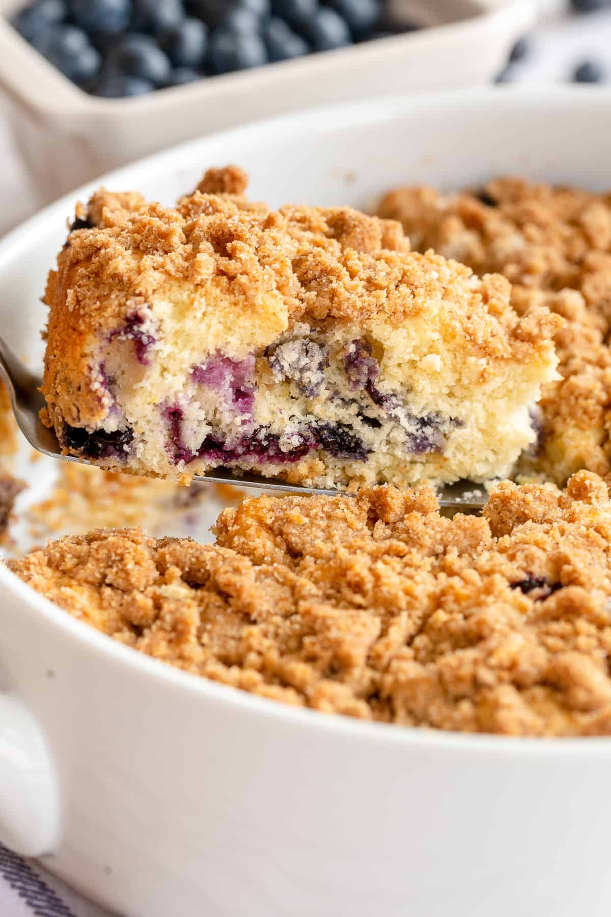 A spatula lifts a slice of crumb cake from a baking dish.