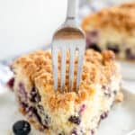 A fork presses into a slice of Blueberry Crumb Cake.