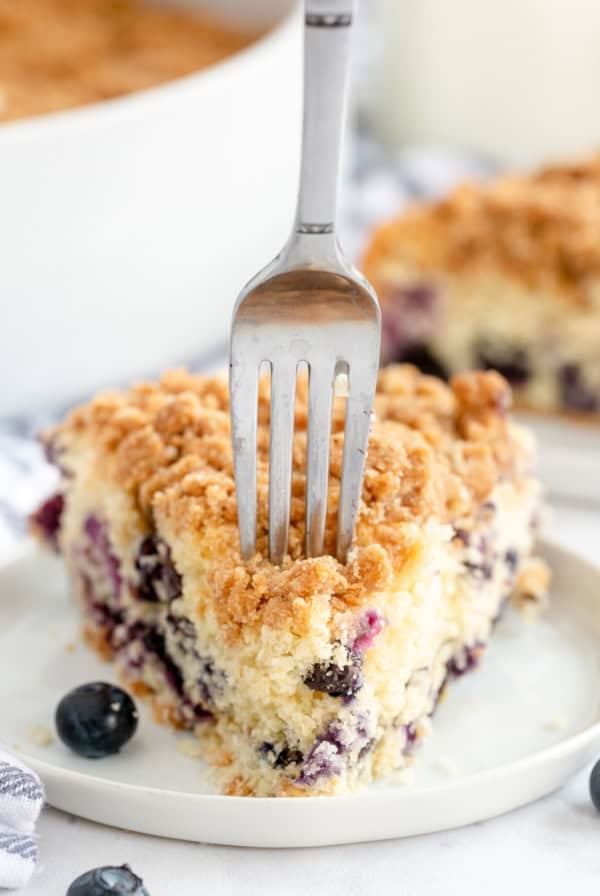 A fork presses into a slice of Blueberry Crumb Cake.